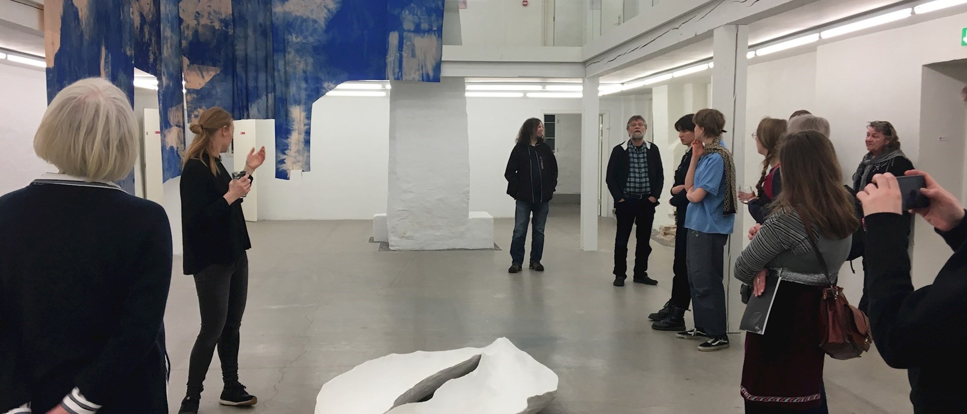 En gruppe mennesker, der høre kunstneren fortælle om udstillingen